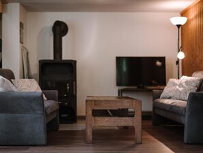 Ein Wohnzimmer mit zwei Sofas, einem kleinen Holztisch, einem Fernseher und einem Kamin.