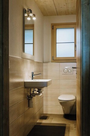 A small bathroom with a sink, mirror, and toilet. - Chalet Christeli Appartement/Fewo, Dusche oder Bad, WC, 4 oder mehr Schlafräume by Interhome (Adelboden)