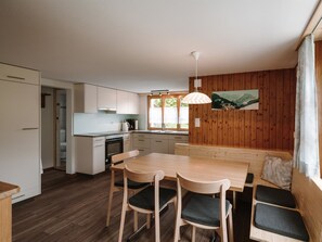 Eine moderne Küche mit Essbereich, Holzvertäfelung und einem großen Fenster.
