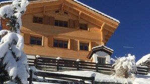 Un edificio cubierto de nieve con una valla de madera y un letrero que dice 'CHRISTELI'.