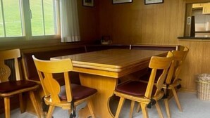 Ein Holzespeisetisch mit sechs Stühlen, ein Fenster mit Vorhängen und gerahmte Bilder an der Wand.