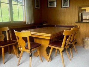 A wooden dining table with six chairs, a window with curtains, and framed pictures on the wall. - Baselbiet Appartement/Fewo, Bad, WC, 3 Schlafräume 4 Zimmerwohnung by Interhome (Adelboden)