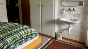 Ein Schlafzimmer mit einem Bett, ein Badezimmer mit einem Waschbecken und einem Spiegel.
