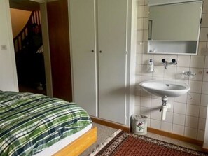 A bedroom with a bed, a bathroom with a sink, and a mirror. - Baselbiet Appartement/Fewo, Bad, WC, 3 Schlafräume 4 Zimmerwohnung by Interhome (Adelboden)