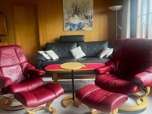 A living room with a black sofa, two red leather armchairs, and a small round table. - Baselbiet Appartement/Fewo, Bad, WC, 3 Schlafräume 4 Zimmerwohnung by Interhome (Adelboden)