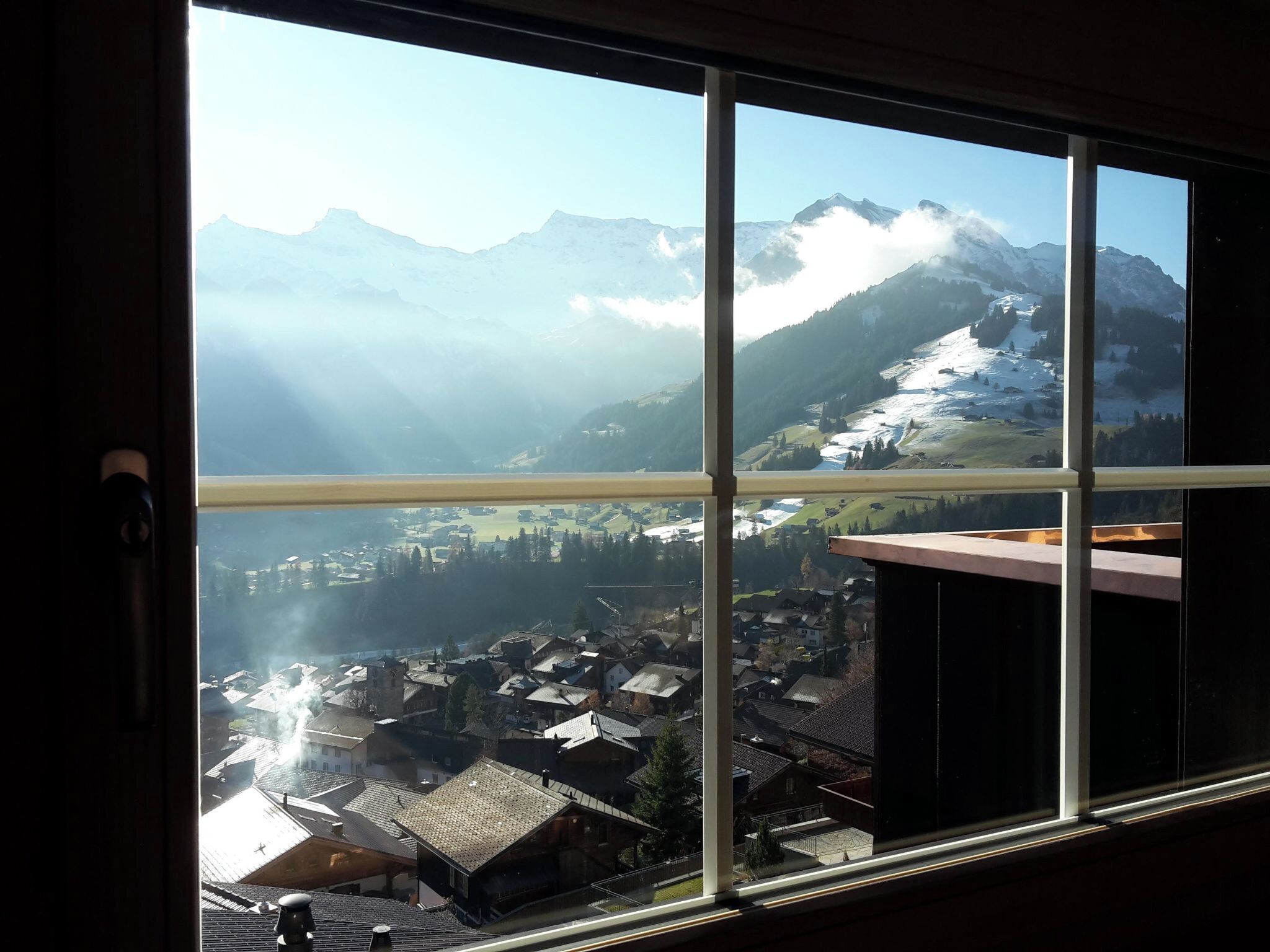 Vista dalla finestra su un paesaggio montano con un villaggio sottostante.