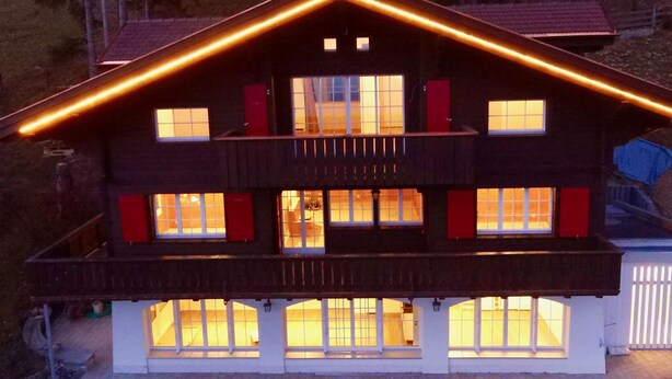 Un bâtiment à deux étages doté d’un balcon, de nombreuses fenêtres et d’un toit orné de décorations lumineuses.