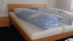 Ein Einzelbett mit Holz Kopfteil und weißer Matratze.