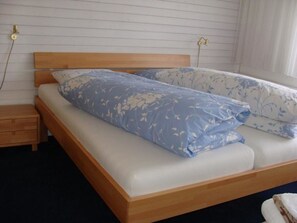 Ein Einzelbett mit Holz Kopfteil und weißer Matratze.