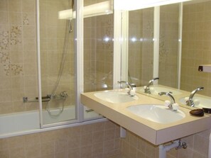 Ein Badezimmer mit zwei Waschbecken, einer Dusche und einer gläsernen Duschkabine.