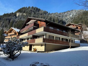 Een chalet met meerdere verdiepingen en balkons, gelegen in een besneeid berglandschap.