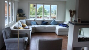 Ein Wohnzimmer mit Ecksofa, einem Sessel, einer Lampe und einem Kamin.