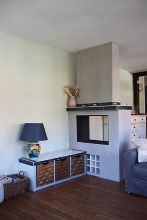 A modern living room with a built-in fireplace, a side table with a lamp, and a sofa. - Lavendel AP C22 Appartement/Fewo, Dusche, WC, 3 Schlafräume 4-Zimmerwohnung by Interhome (Adelboden)