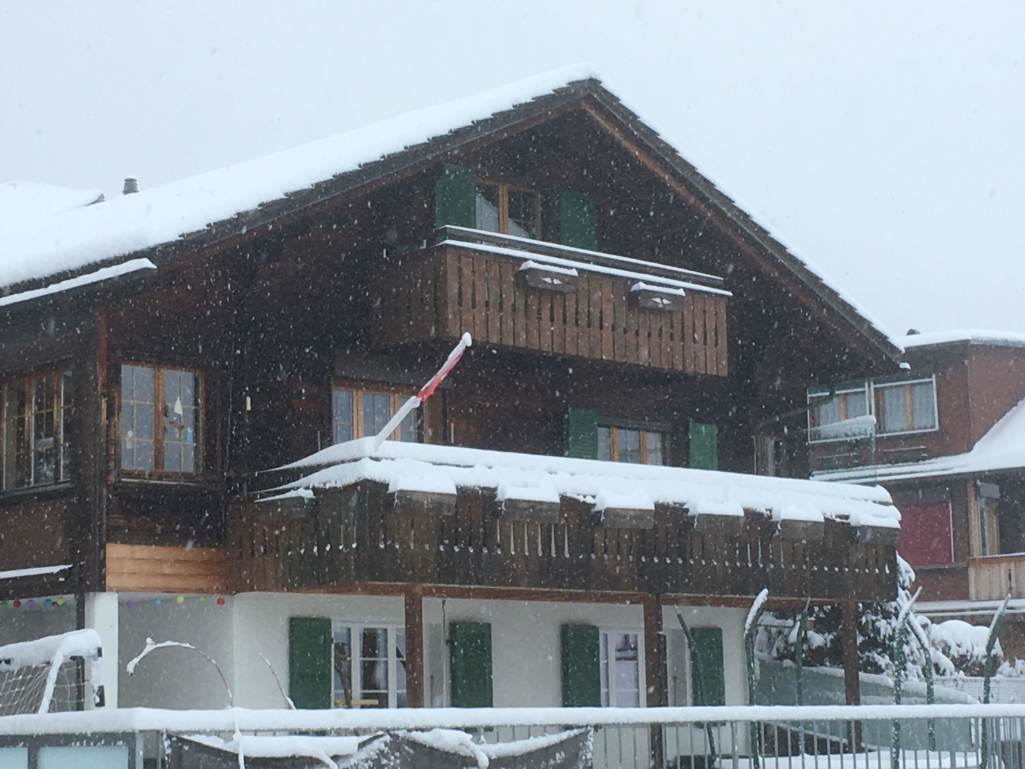 Un edifici de fusta de dos pisos amb un balcó, envoltat de neu.
