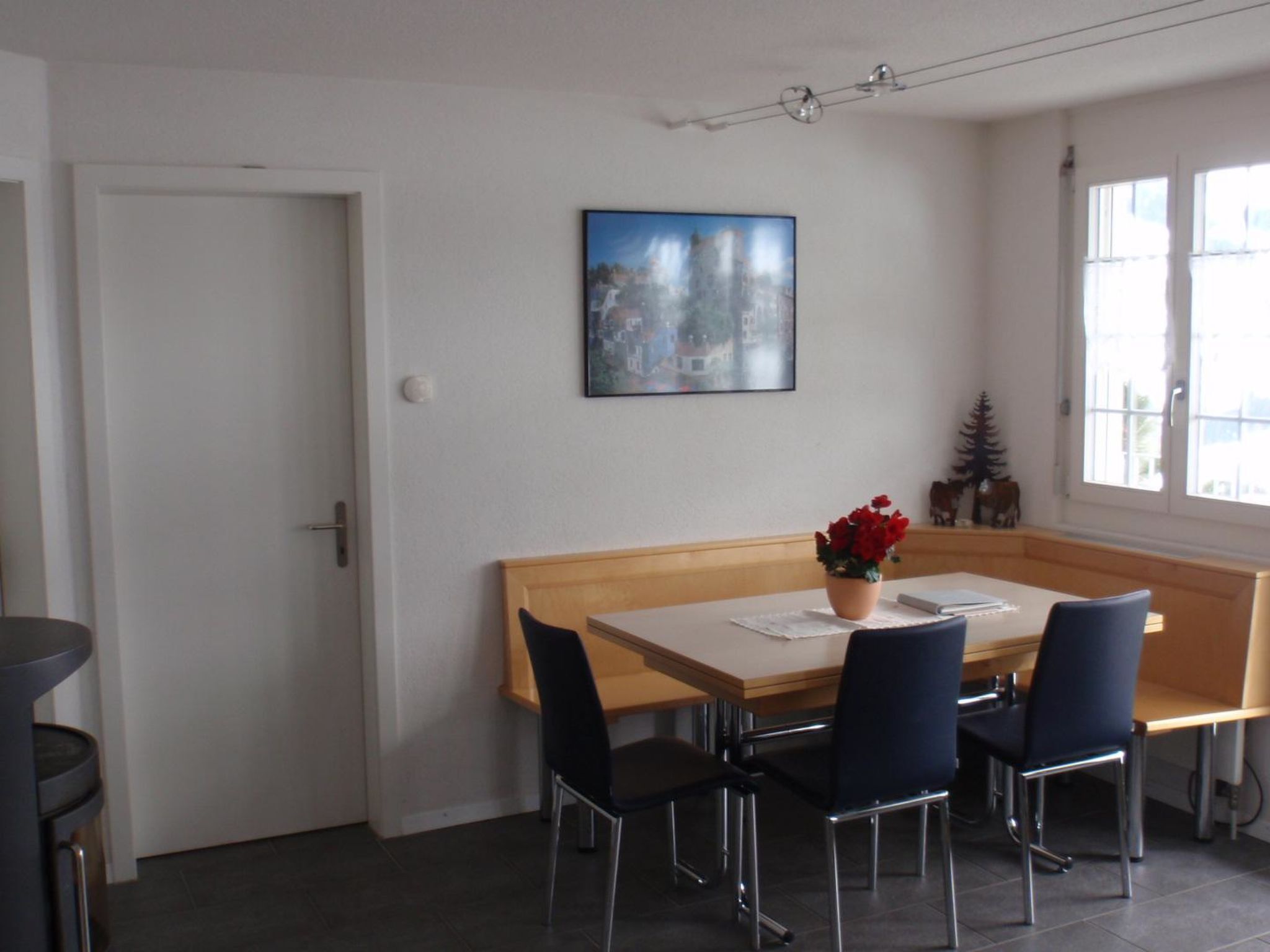 A dining area with a table, chairs, and a potted plant.