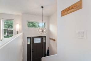 Un escalier agrémenté d’un luminaire fixé au mur et d’un lustre suspendu au plafond.