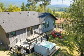 Une maison avec une terrasse, un espace salon extérieur et un jacuzzi.