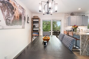 A modern kitchen with a dark wood floor, a central island, and a view to an outdoor patio. - Whitefish Mountain Retreat with Hot Tub, Fire Pit & Heated Garage (Whitefish)