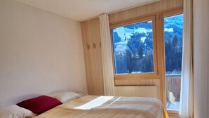 A bedroom with a large bed, a window with a view of a snowy landscape, and a ceiling light fixture. - Chalet Sirius Appartement/Fewo, Bad, WC, 3 Schlafräume 4-Zimmer-Wohnung by Interhome (Adelboden)