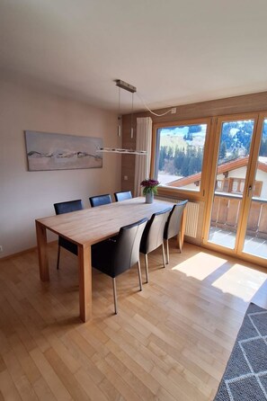 A spacious dining area with a wooden table and chairs, a large window with a view of a mountainous landscape, and a modern pendant light. - Chalet Sirius Appartement/Fewo, Bad, WC, 3 Schlafräume 4-Zimmer-Wohnung by Interhome (Adelboden)