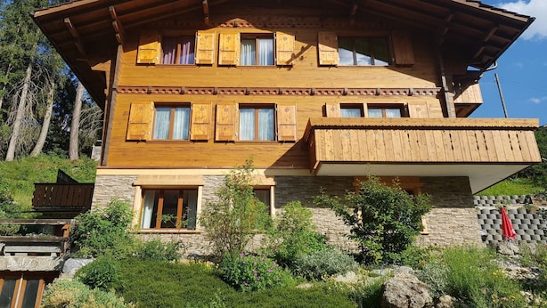 A multi-story wooden chalet with a sloped roof, stone foundation, and a balcony. - Grüneggli Appartement/Fewo, Bad, WC, 2 Schlafräume 3.Zimmerwohnung by Interhome (Adelboden)