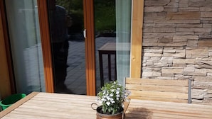A wooden table with a potted plant, a chair, and a view of a mountainous landscape through a glass door. - Grüneggli Appartement/Fewo, Bad, WC, 2 Schlafräume 3.Zimmerwohnung by Interhome (Adelboden)