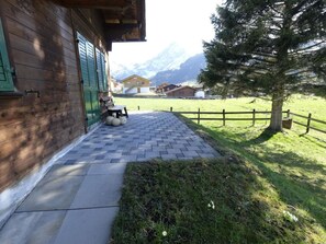 A wooden building with a paved entrance and a grassy area with a tree. - Wildrösli Appartement/Fewo, Dusche, WC, 2 Schlafräume 3-Zimmerwohnung 1.Stock by Interhome (Adelboden)