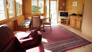 Ein gemütliches Zimmer mit einer Couch, einem Esstisch mit Stühlen, einem Fernseher und Holzschränken.
