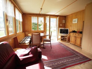Ein gemütliches Zimmer mit einer Couch, einem Esstisch mit Stühlen, einem Fernseher und Holzschränken.