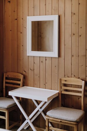 A room with wooden panel walls, a white-framed mirror, and two wooden chairs with cushions. - Marlis Appartement/Fewo, Bad, WC, 2 Schlafräume 3-Zimmerwohnung 1.Stock by Interhome (Adelboden)