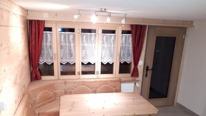 Ein Essbereich mit Holztisch und -stühlen, einem Fenster mit Vorhängen sowie einer Tür.
