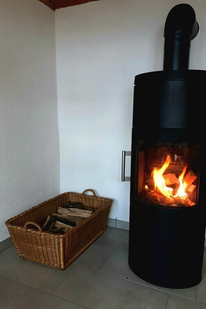 Ein Kaminofen mit einem Holzkorb daneben.