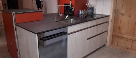 Une cuisine compacte équipée d’un lave-vaisselle, d’une machine à café et d’un évier.