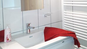Ein Badezimmer mit einem weißen Waschbecken, einem Spiegel und einem roten Handtuch.