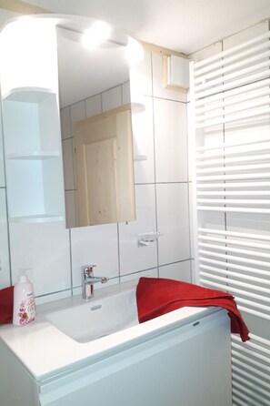 A bathroom with a white sink, a mirror, and a red towel. - Wanni Appartement/Fewo, Bad, WC, 3 Schlafräume 4-Zimmerwohnung by Interhome (Frutigen)