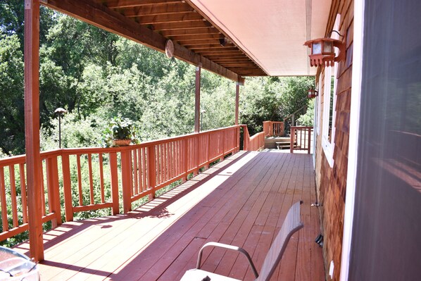 A wooden deck with a railing, a bench, and a potted plant.