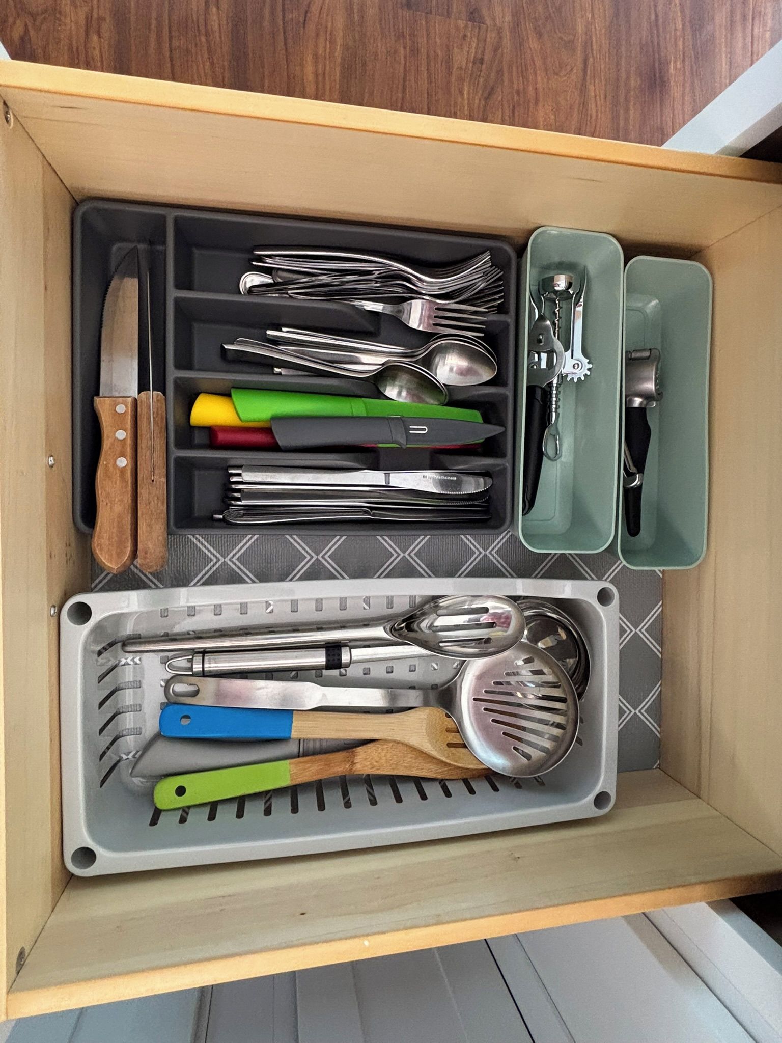 Un cajón con diversos utensilios de cocina organizados en compartimentos.