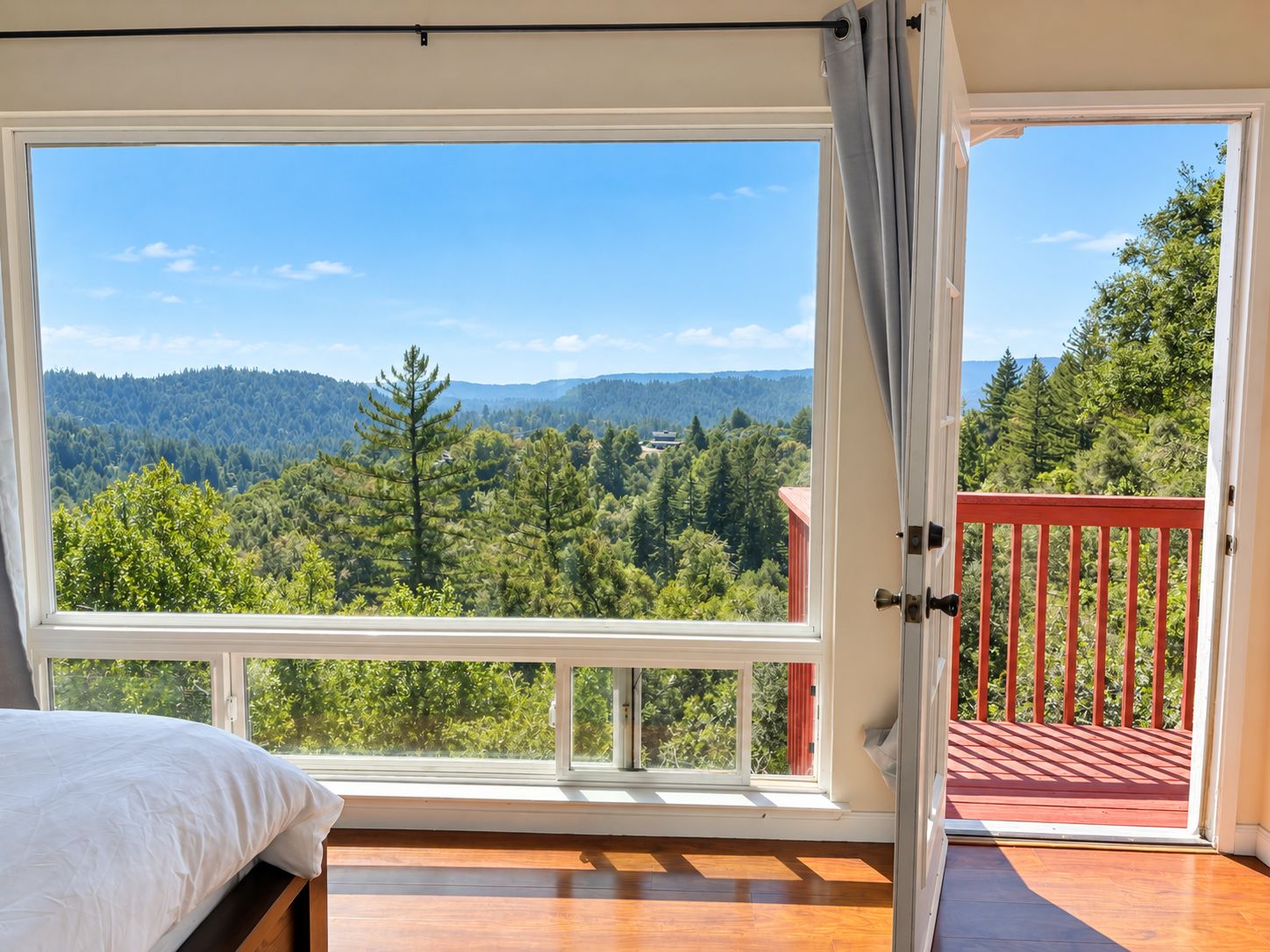 Un dormitorio con un amplio ventanal que ofrece vistas a un paisaje boscoso.