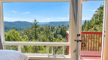 Un dormitorio con un amplio ventanal que ofrece vistas a un paisaje boscoso.