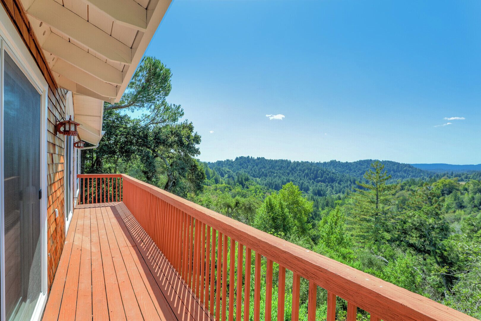 Une terrasse en bois dotée d’une rambarde, qui offre une vue sur un paysage boisé.