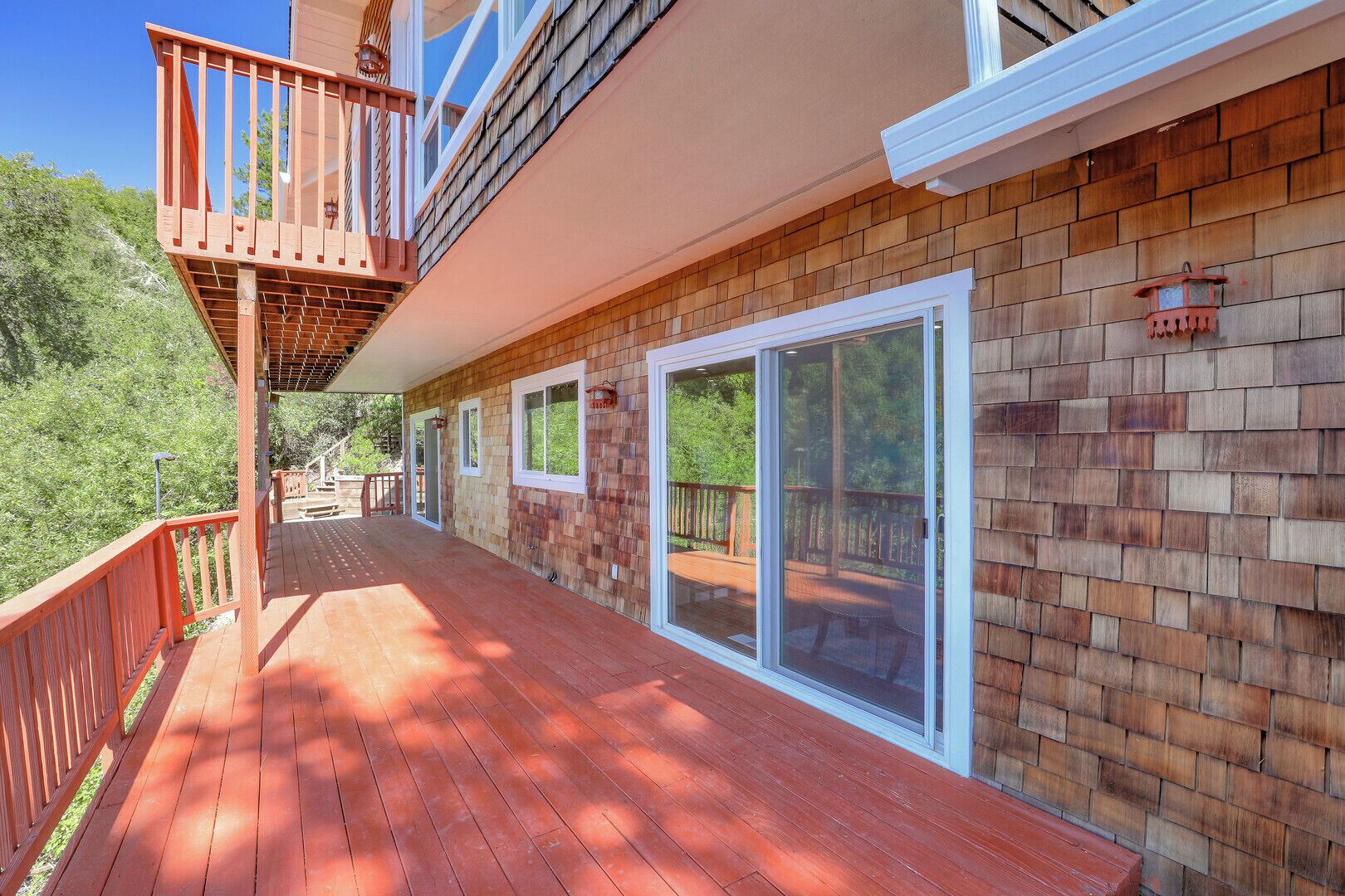 A wooden deck with a glass door leading to a covered outdoor area.