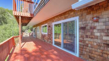 A wooden deck with a glass door leading to a covered outdoor area.