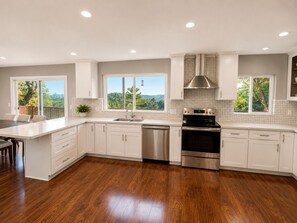 A modern kitchen with white cabinetry, a stainless steel dishwasher, and an oven.
