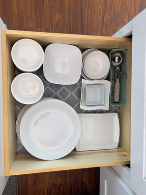 A drawer containing various white dishes and a set of keys.