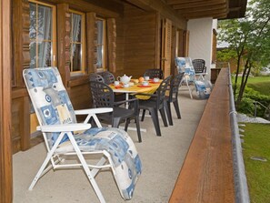 An outdoor dining area with a wooden deck, a table set with chairs, and a view of the surrounding greenery. - Mi Casa Appartement/Fewo, Bad, WC, 3 Schlafräume 3-Zimmerwohnung 1.Stock by Interhome (Adelboden)