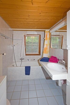 A bathroom with a bathtub, a shower, a sink, and a window. - Mi Casa Appartement/Fewo, Bad, WC, 3 Schlafräume 3-Zimmerwohnung 1.Stock by Interhome (Adelboden)