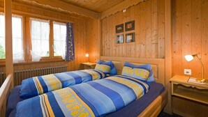 Una camera in una baita di legno con un letto matrimoniale, due comodini e una finestra con tende.