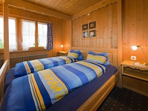 Ein Zimmer in einer Holzhütte mit einem Doppelbett, zwei Nachttischen und einem fenster mit Vorhängen.