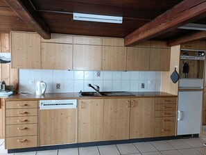 Una cocina con armarios de madera, lavavajillas, fregadero y refrigerador.