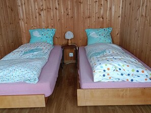 A room with two single beds, each with a polka dot bedspread and matching pillows, a wooden headboard, and a nightstand with a lamp. - Bim Lerch Appartement/Fewo, Bad, WC, 3 Schlafräume 4.5-Zimmerwohnung by Interhome (Adelboden)